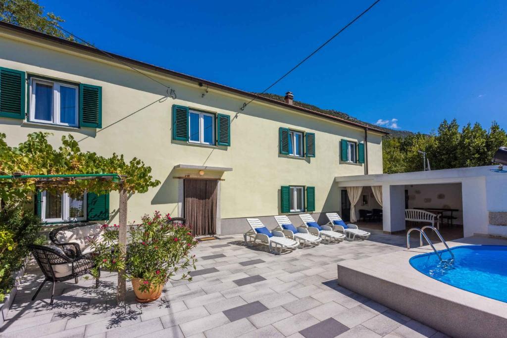 DomijančićiHoliday home in Drivenik 41881的一座房子前面设有游泳池和椅子