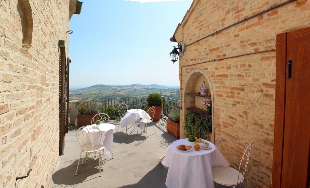 a patio with white tables and chairs and a building at Dedicato A Te in Montelupone