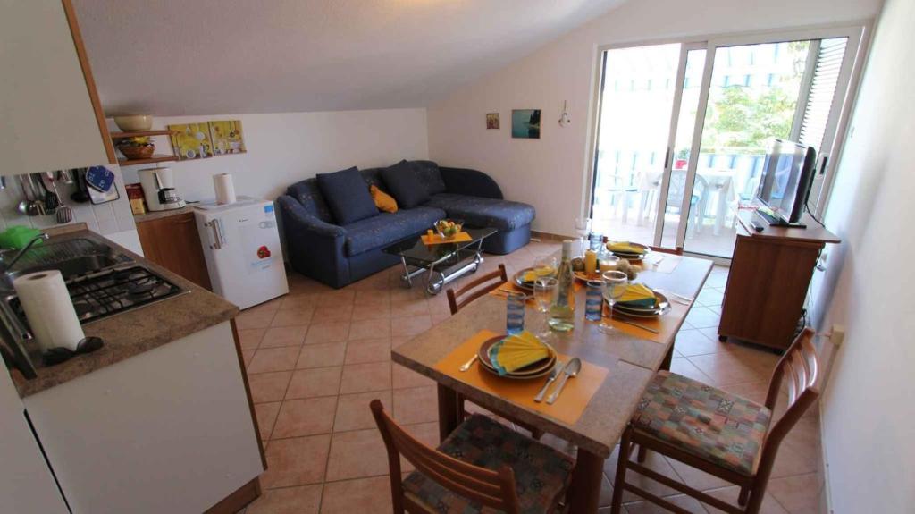 Una cocina y una sala de estar con una mesa y un sofá azul. en Apartment in Porat - Insel Krk 13205, en Porat