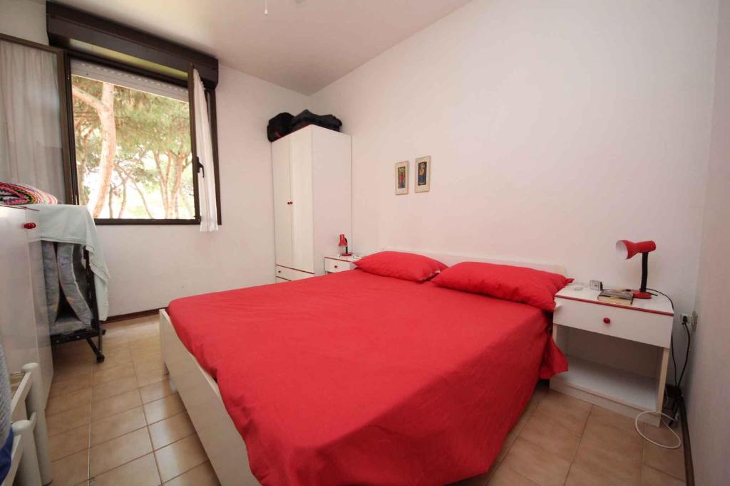 a bedroom with a red bed and a window at One-Bedroom Apartment in Rosolina Mare V in Rosolina Mare