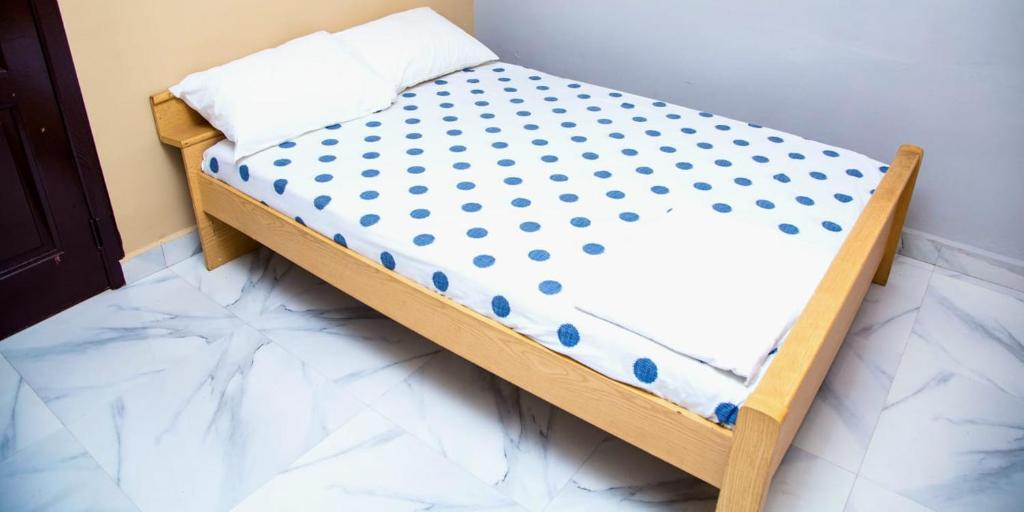 Una cama pequeña con lunares azules. en Eliogemi Guest Room, en Gbawe