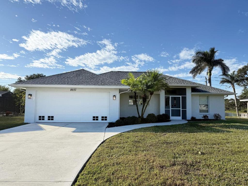 a white house with a driveway and palm trees at Pet-Friendly 3BR – Relax & Explore Beaches & Golf in Rotonda