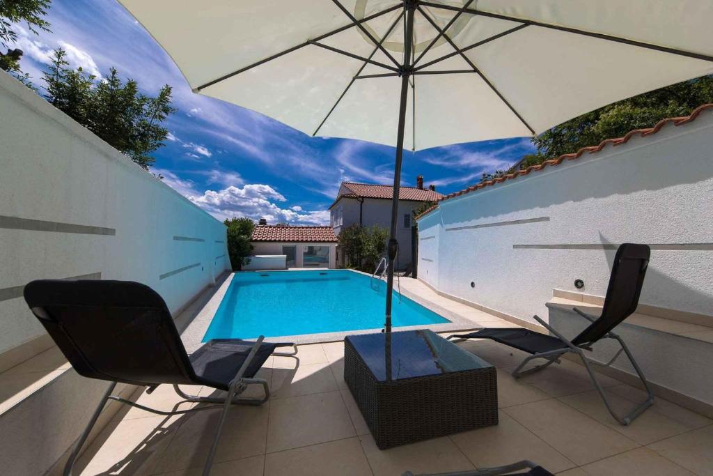 a swimming pool with two chairs and an umbrella at Apartment in Crikvenica 41676 in Sopaljska