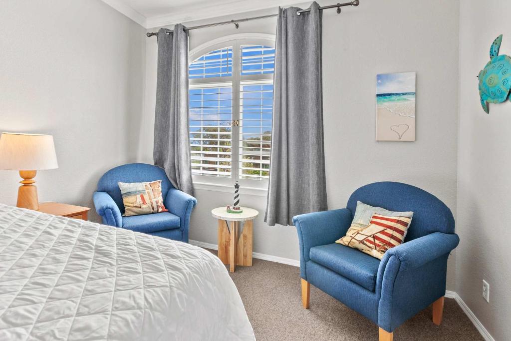 a bedroom with two blue chairs and a bed and a window at Coastal Cutie in Oceano