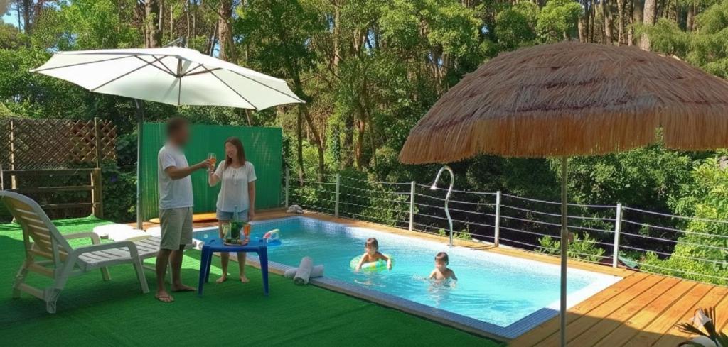 zwei Personen stehen neben einem Pool mit Sonnenschirm in der Unterkunft Casa Gloria con Piscina - Jacuzzi exterior climatizada Relax Playa in Punta del Este