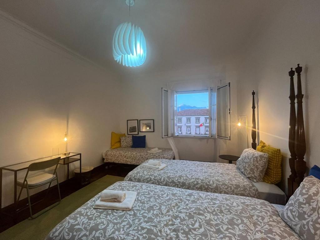 a hotel room with two beds and a window at AP Piso 2 inteiro · Portas Residence, o mais central de Ponta Delgada! in Ponta Delgada