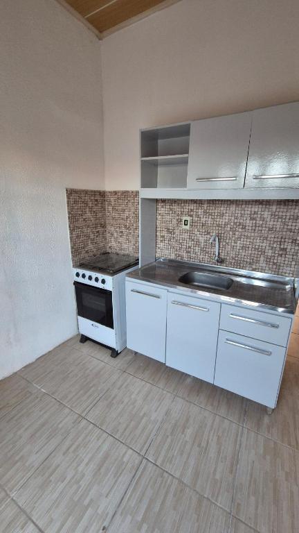 a kitchen with white cabinets and a sink at Apartamento pequeno central in Santa Vitória do Palmar