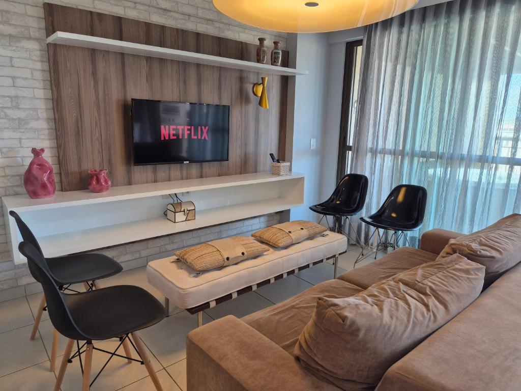 sala de estar con sofá, TV y sillas en Cobertura Duplex - Luxo com Jacuzzi e 3 Suítes, en Aquiraz