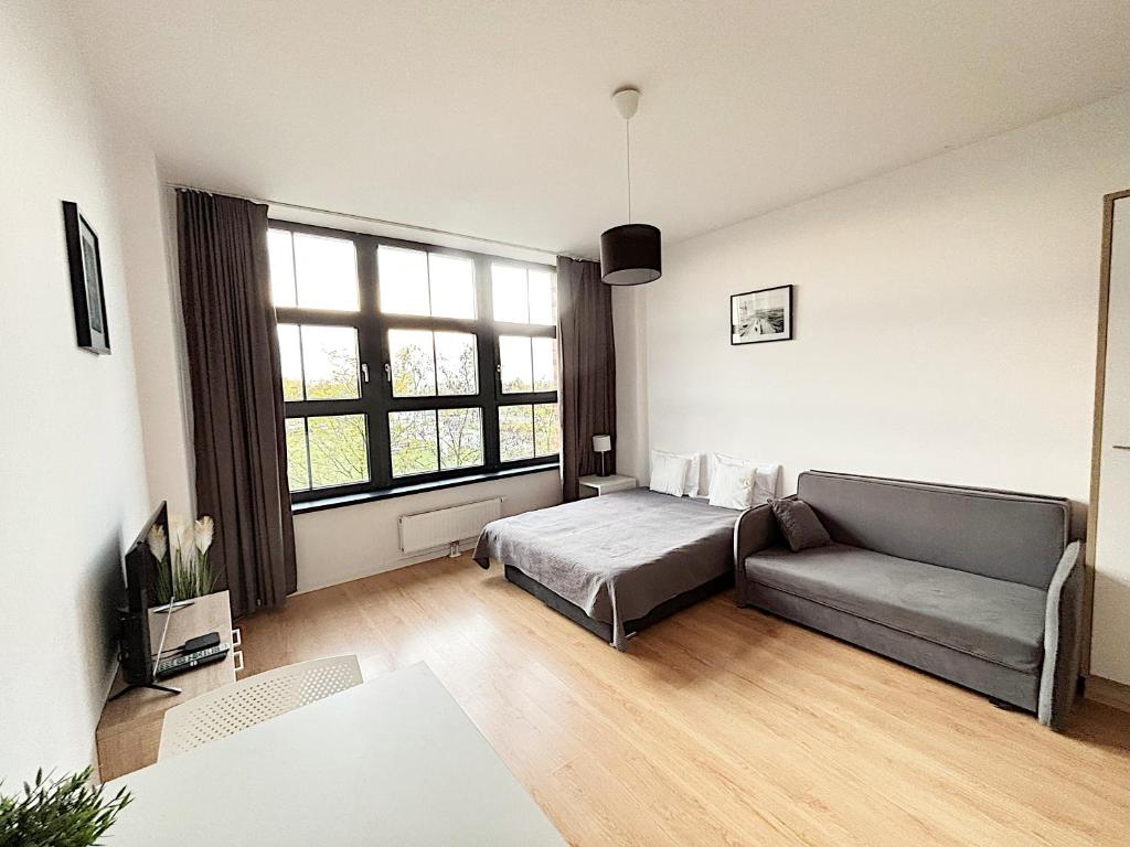 Una sala de estar con un sofá y una ventana grande. en Apartimento Hydral Arte, en Wroclaw