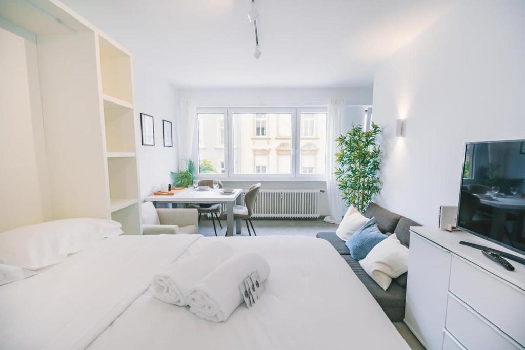 een witte slaapkamer met een groot bed en een woonkamer bij Stylish Studio in the Heart of Luxembourg City in Luxemburg
