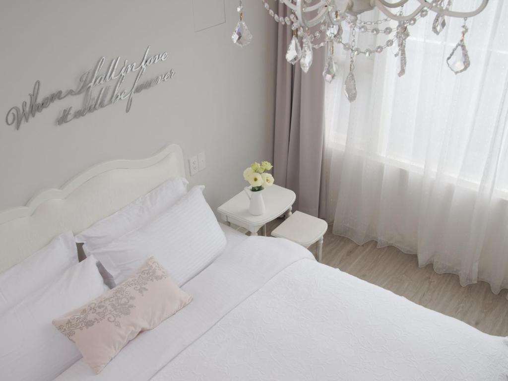 Habitación blanca con cama blanca y lámpara de araña. en White Truffle B&B, en Luodong