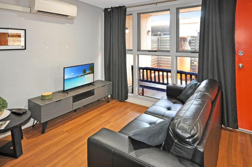 a living room with a couch and a television at Stylish Studio 1x1 Walk to CBD in Port Hedland