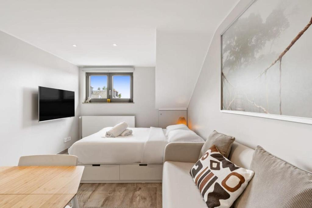 a white bedroom with a bed and a couch at Modern Limpertsberg Studio Near City Center in Luxembourg