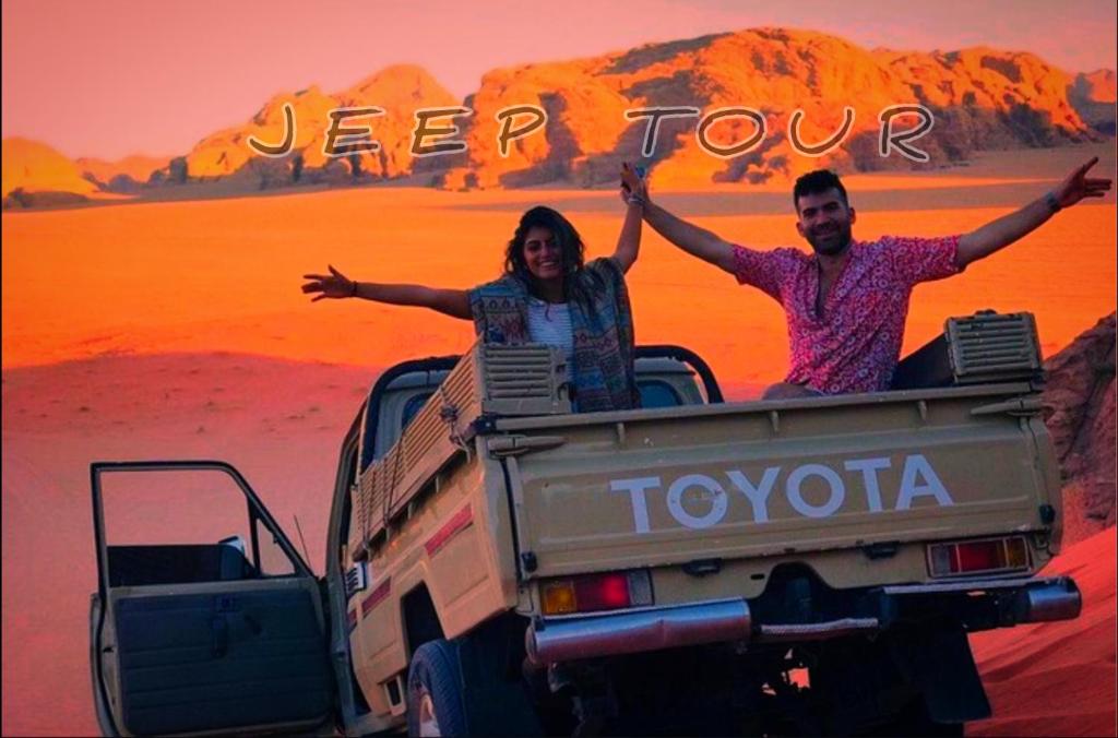 a man and woman riding in the back of a truck at WADI RUM NEOM lUXURY CAMP in Wadi Rum
