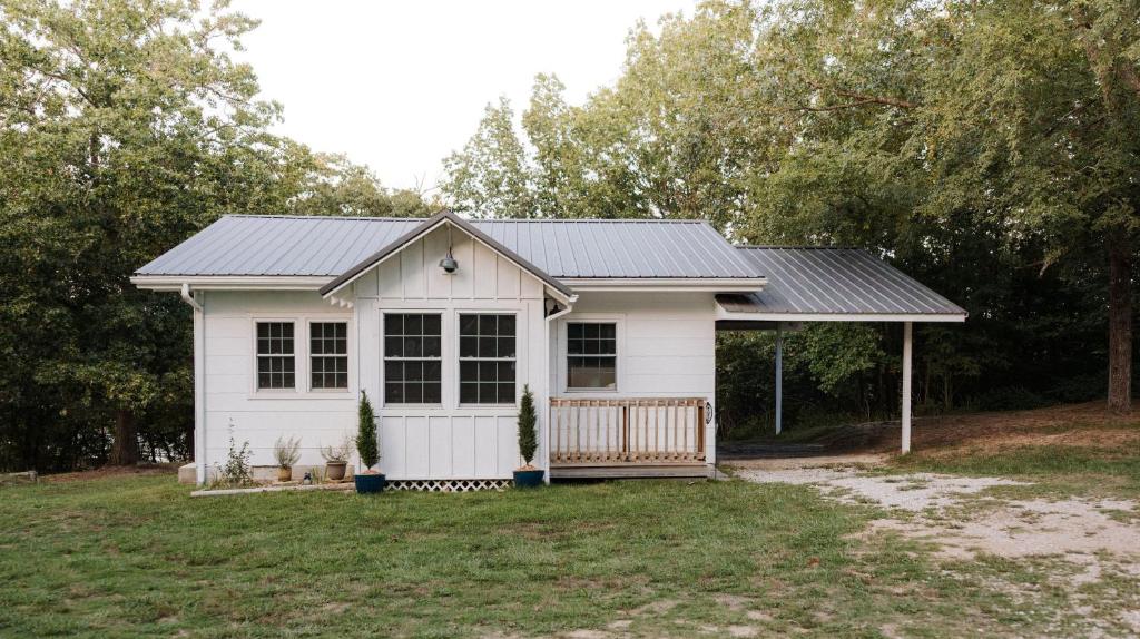 ein kleiner weißer Schuppen mit schwarzem Dach in der Unterkunft Belle Cottage in Eagle Rock