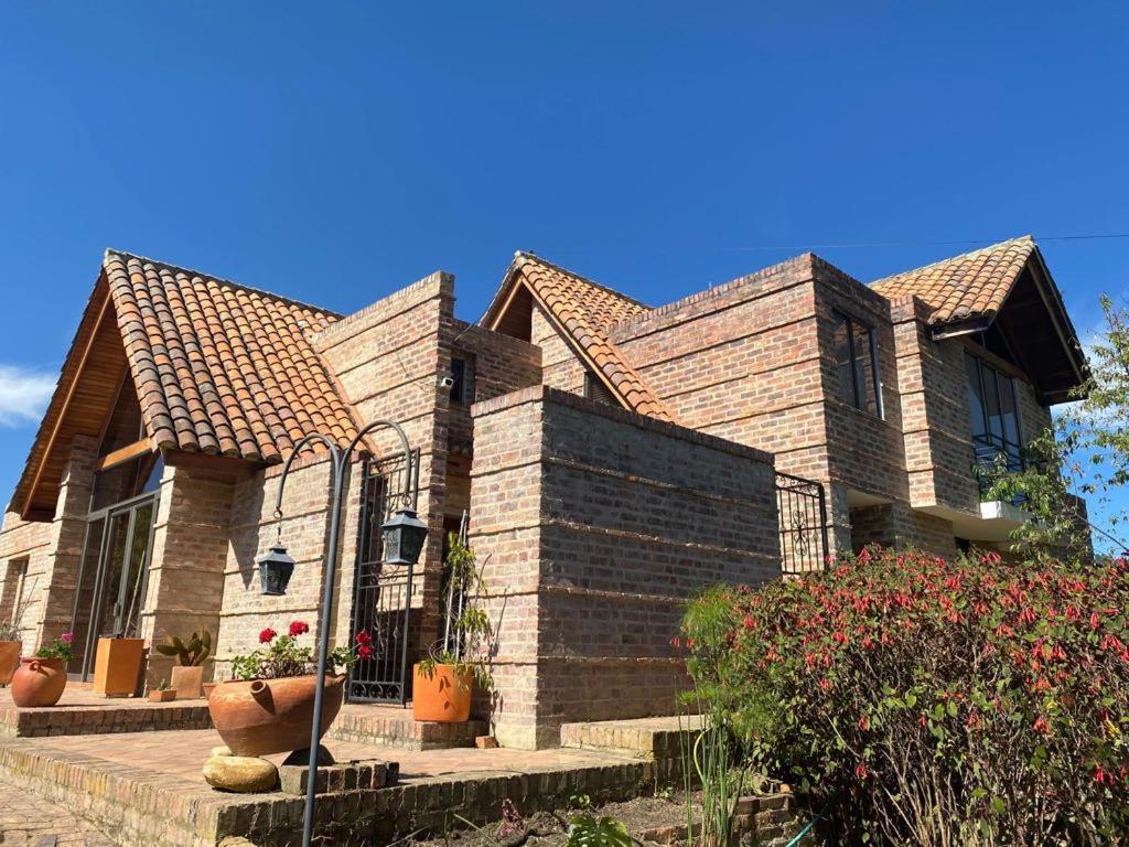 a large brick house with a large vase in front of it at Cabaña campestre Villa Maria in Tuta