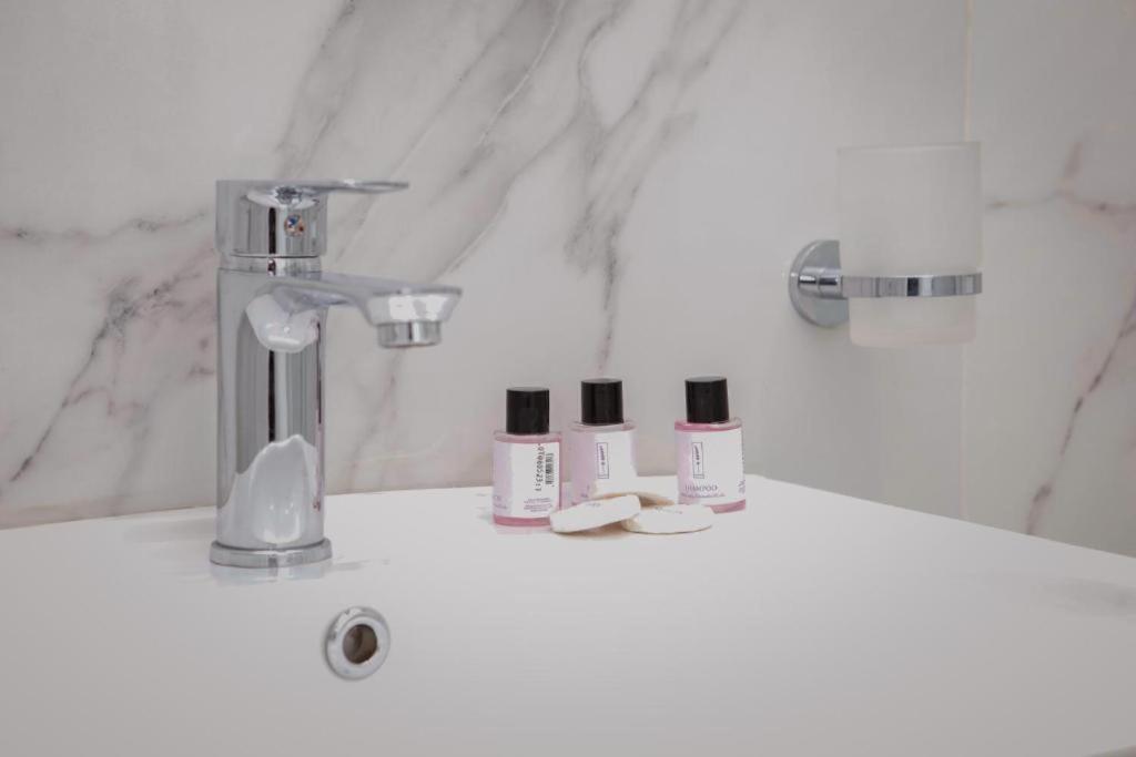 a bathroom sink with three products on it at Hermes Petite Maison Hotel in Tirana