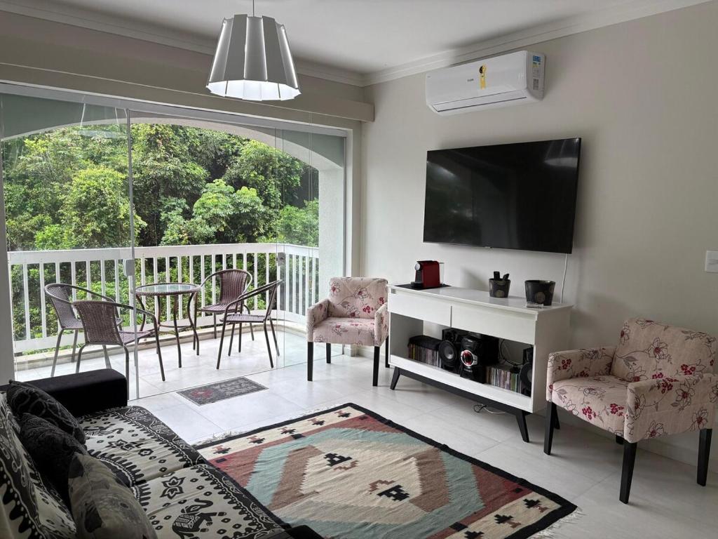 a living room with a couch and a tv at Apartamento completo, 200mts da praia de Pitangueiras in Guarujá