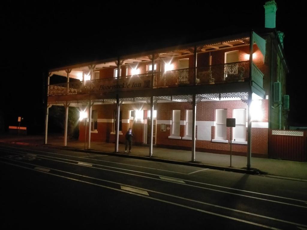 a person standing in front of a building at night at Honeysuckle Inn - Violet Town in Violet Town