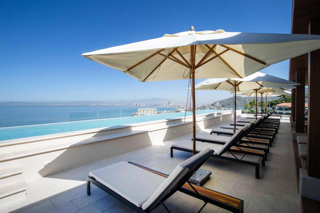 een rij ligstoelen en parasols op een balkon bij Huge Balcony with BBQ, Rooftop Pool and Ocean Views in Puerto Vallarta