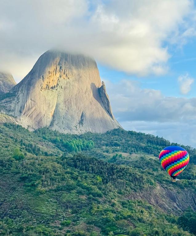 a hot air balloon flying in front of a mountain at Apartamento quarto e sala, varanda com vista para a Pedra Azul e cozinha completa no Condomínio Vista Azul in Pedra Azul