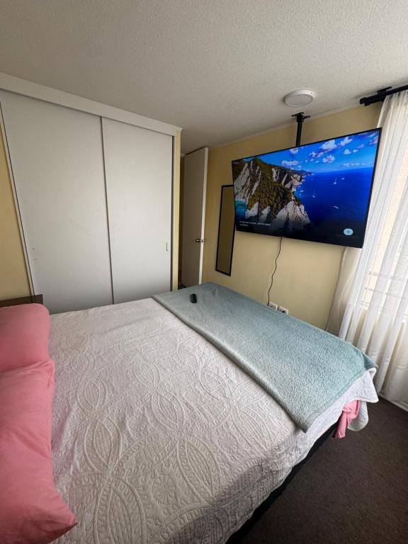 um quarto com uma cama grande e uma TV de tela plana em Condominio Viña Oriente 2 em Viña del Mar