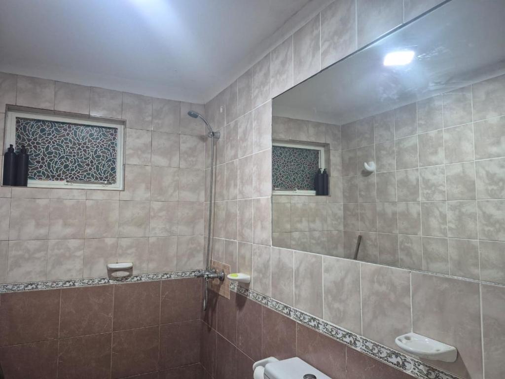 ein gefliestes Bad mit einer Dusche und einem Spiegel in der Unterkunft Casa en Pueblo Esther in Pueblo Esther