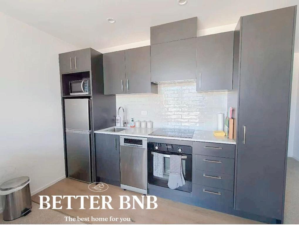 een keuken met grijze kasten en een koelkast bij Free Parking AC Cooling and CBD View in Wellington