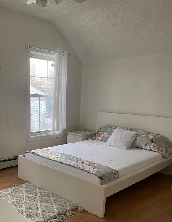 Una habitación blanca con una cama y una ventana en Simple room, en Paterson