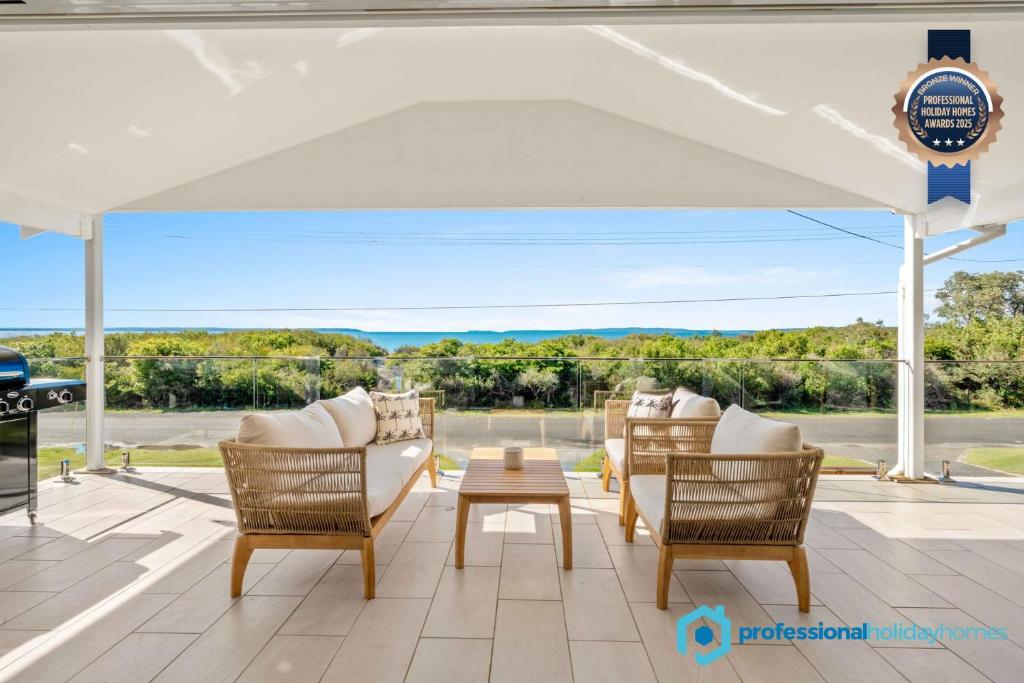 a patio with a white canopy and chairs and a table at Callala Beach Walk - Beachfront with Fireplace in Callala Beach