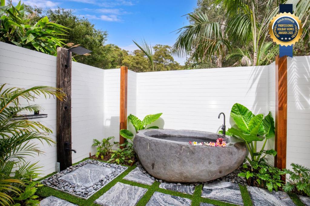a bathtub in a garden with a fence at Rest Pet Friendly with Outdoor Bath 3 Mins Walk to Beach in Umina