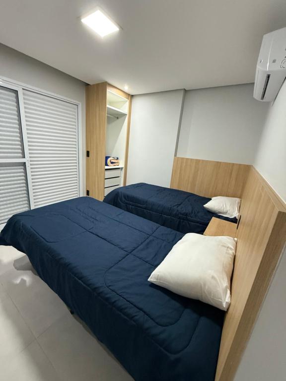 1 Schlafzimmer mit 2 Betten und blauer Bettwäsche in der Unterkunft Priority Praia Grande in Praia Grande