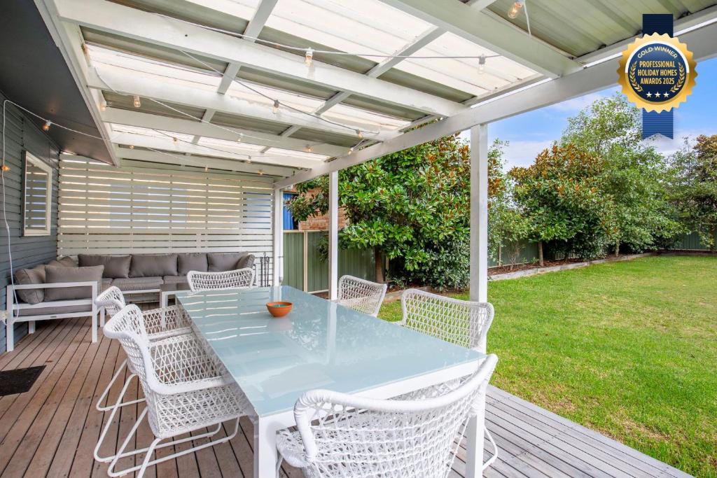 a patio with a table and chairs on a deck at Hayes Beach House I Award Winner I 4 Mins to Beach in Callala Beach