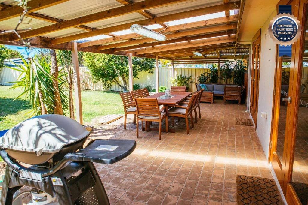 een patio met een tafel en stoelen en een motorfiets bij Sunbaker Pet Friendly Awards Finalist 4 Mins Walk to Culburra Beach in Culburra Beach