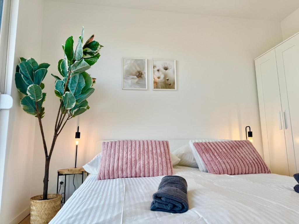 a bedroom with a bed with two pillows and a plant at Modern Apartment with Balcony near Vienna in Wiener Neudorf