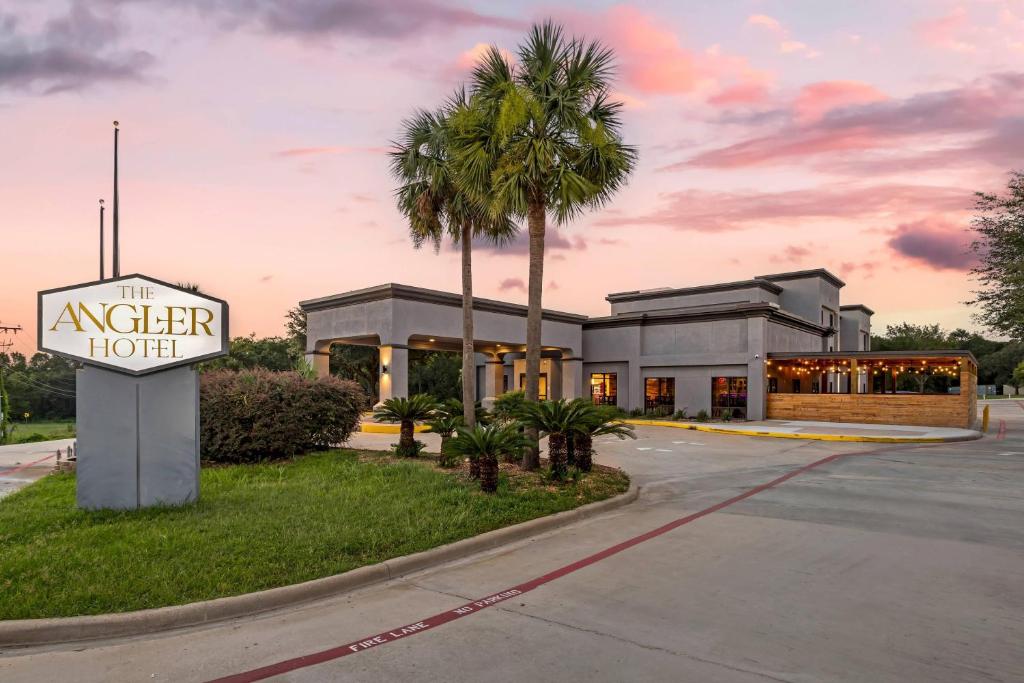 a hotel with a motel sign and a palm tree at The Angler Hotel Livingston, an Ascend Collection Hotel in Livingston