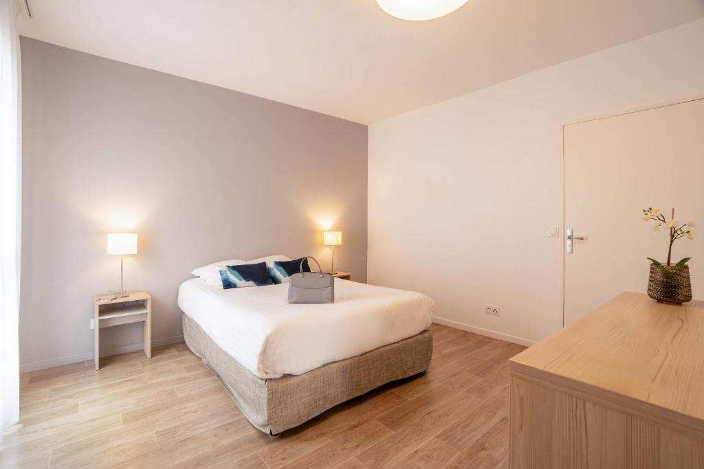 a white bedroom with a bed and a mirror at Quality Aparthotel Bourgoin-Jallieu in Bourgoin
