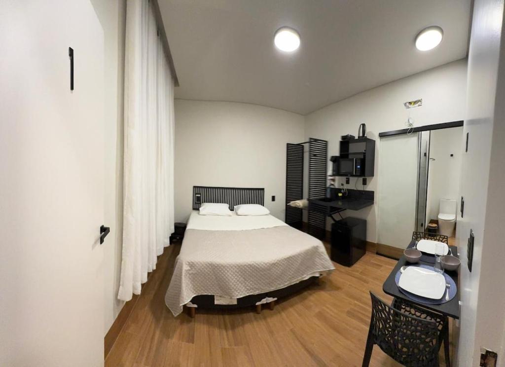 a bedroom with a bed and a desk with a sink at 1Kitnet ao lado da Praça Leonardo Venerando in Lavras