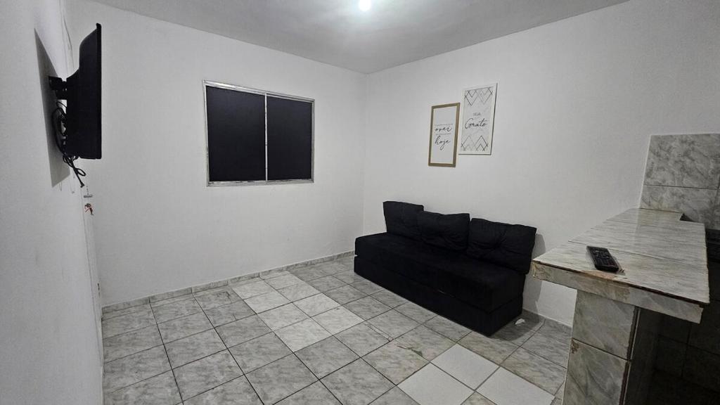 een woonkamer met een zwarte bank en een tafel bij Casa com Quarto e Garagem, Alto da Cruz, Camaçari in Camaçari
