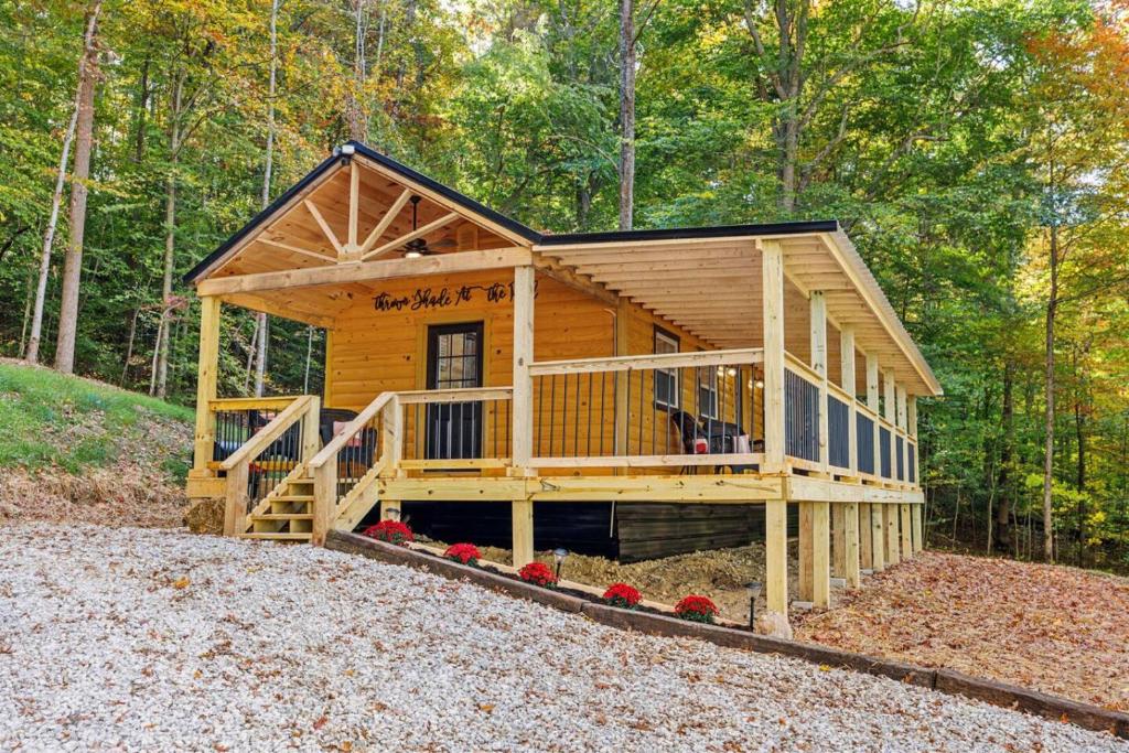 a log cabin with a porch in the woods at Throw'n Shade at the Red - near RRG KY in Stanton