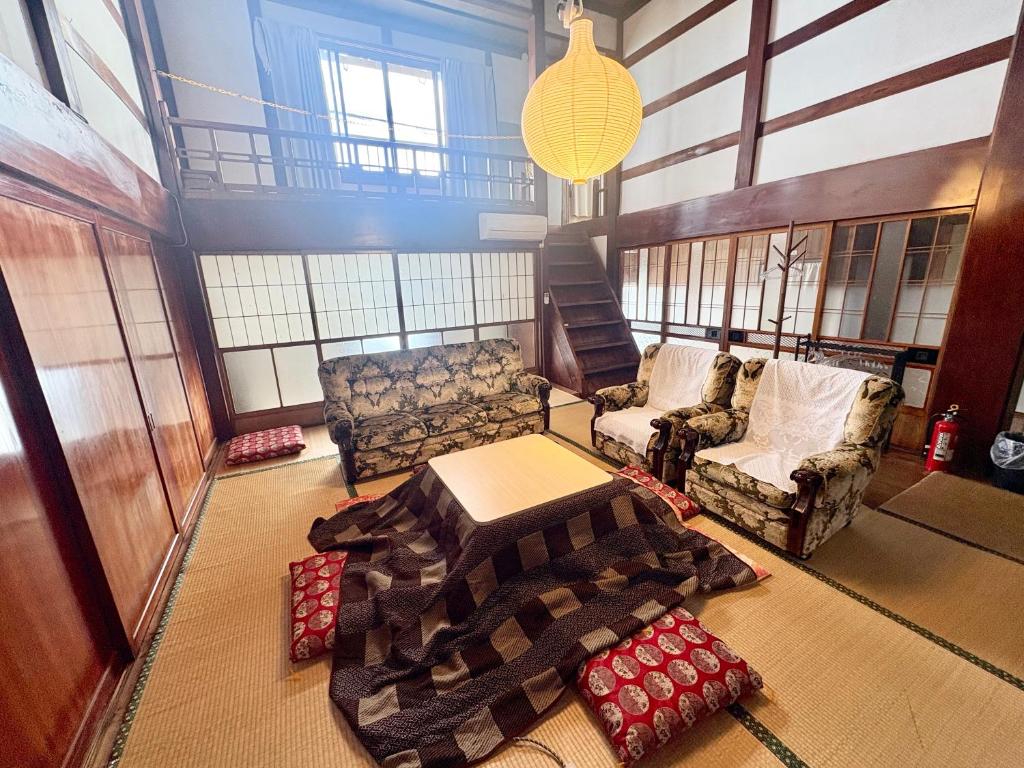 a living room with a couch and a table and chairs at 自然に囲まれた海沿いの広い一軒家 貸切 佐渡 古民家 レッドジャスパーRedjasper in Sado