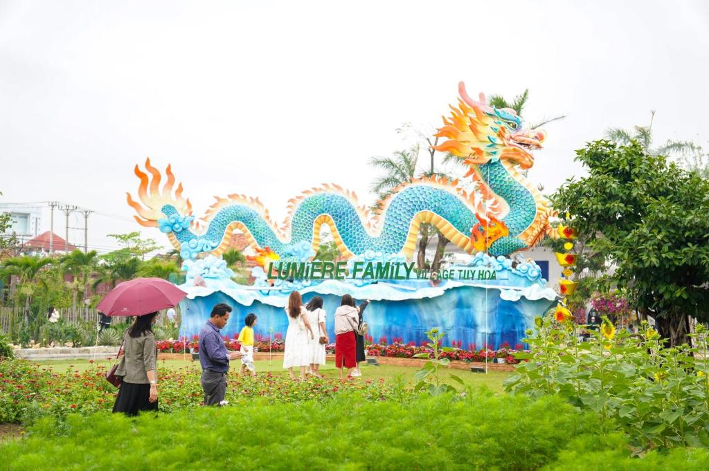 Un groupe de personnes se tient devant un char en forme de dragon dans l'établissement Lumiere Family Village Đông Tác, à Hiếu Xương