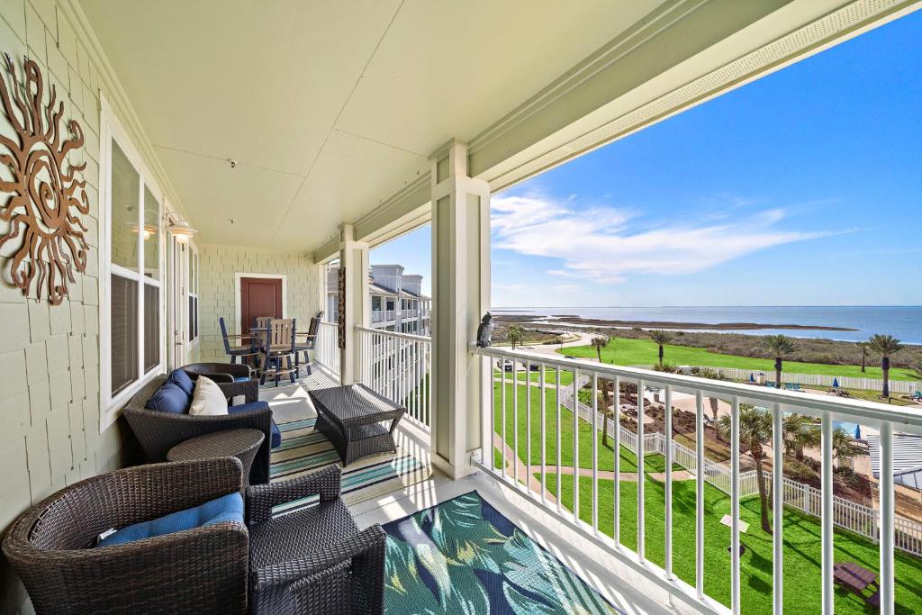 a balcony with chairs and a view of the ocean at Pointe West 302 - Sunset on the Bay in Galveston