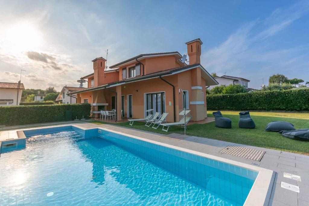 a house with a swimming pool in front of a house at Houses and Apts. in Albarella 24882 in Palazzo Vianello