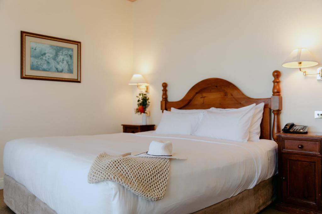 a bedroom with a large white bed with a wooden headboard at Mountain Heritage Hotel in Katoomba