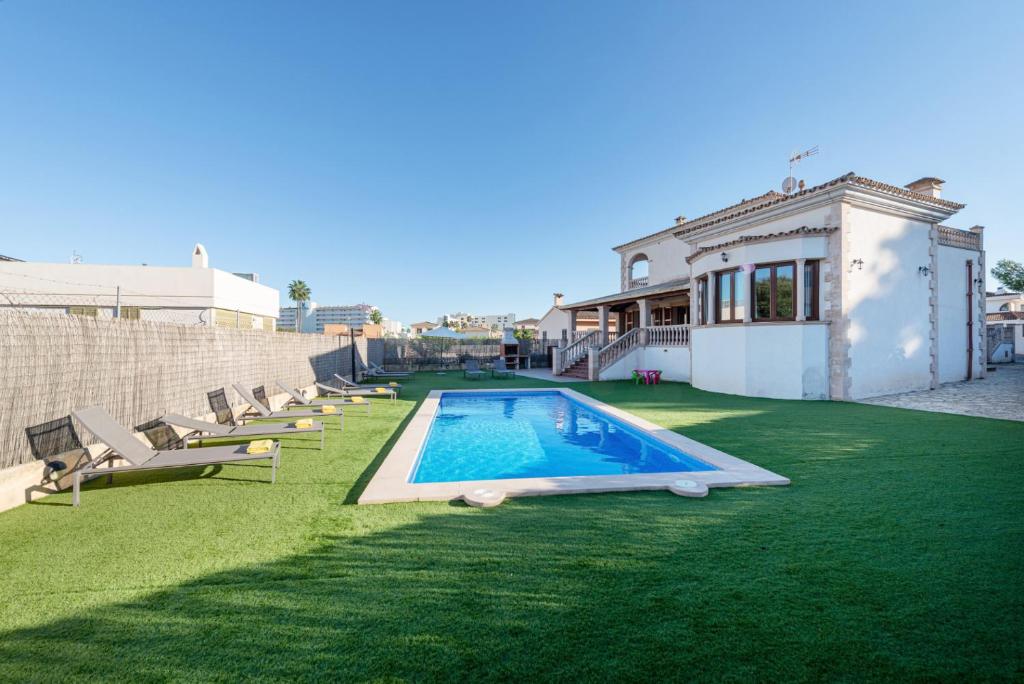 a backyard with a swimming pool and chairs and a house at Cas Fraus in Sa Coma