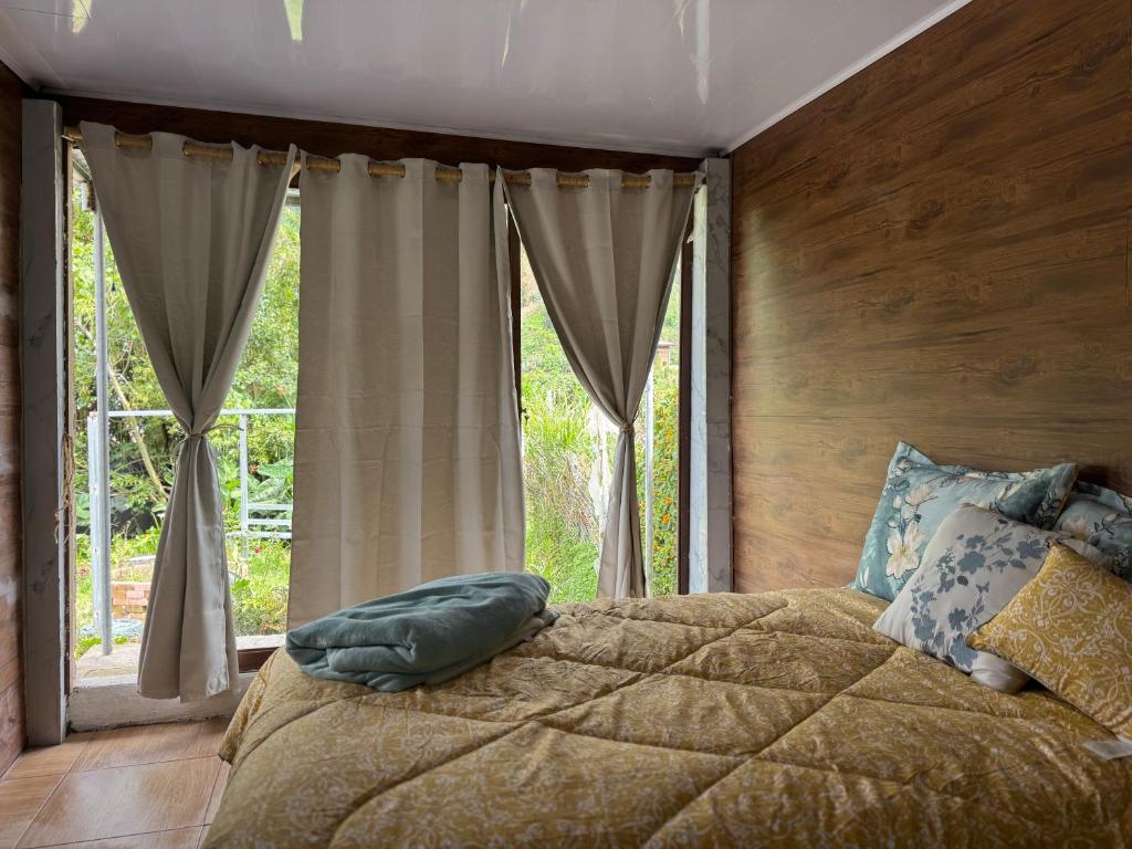 a bedroom with a bed with a large window at Eco Amigo el Rincón in Cerro Punta