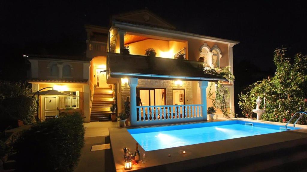 ein Haus mit Pool davor in der Nacht in der Unterkunft Apartments in Lovran 15143 in Lovran