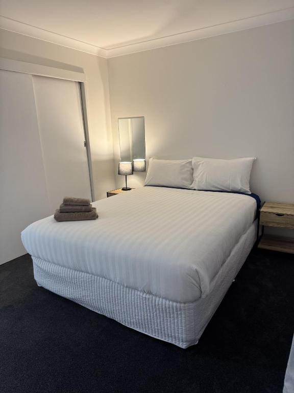 a bedroom with a large white bed with a lamp at Walcha Villas in Walcha