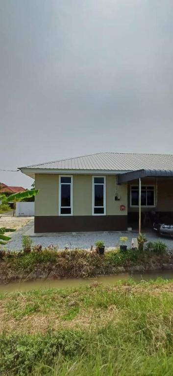 a green house with a car parked in front of it at d'esaku homestay in Penaga